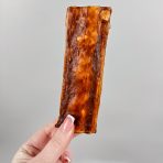 6"x2" flat Collagen dog chew being held by a female hand