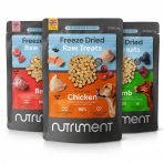 A square professional product photograph showcasing three varieties of Nutriment Freeze Dried Raw Treats for adult dogs. The pouches are arranged in a clean, staggered row against a solid white background. The central pouch features the "Chicken" variety with its distinctive orange label and Golden Retriever mascot. To the left is the "Beef" variety with a red label and Jack Russell Terrier, and to the right is the "Lamb" variety with a green label and Dachshund. Each charcoal grey resealable bag displays "Bite-Sized Raw Rewards," a "Made in the UK" logo, and high-quality images of the natural ingredients like squash, berries, and raw meat