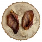 overhead shot of 2 XL pig Ears natural dog treats displayed on a cross section of wooden log