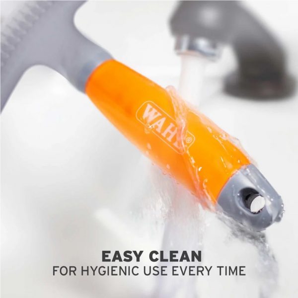 WAHL Double Row Rake Shedding Blade Easy Clean 1080px Close-up lifestyle shot of the WAHL grooming brush being rinsed directly under a running chrome tap. Water flows over the translucent orange gel handle and the grey plastic base, emphasizing its waterproof and low-maintenance design. Bold text at the bottom reads "EASY CLEAN FOR HYGIENIC USE EVERY TIME"
