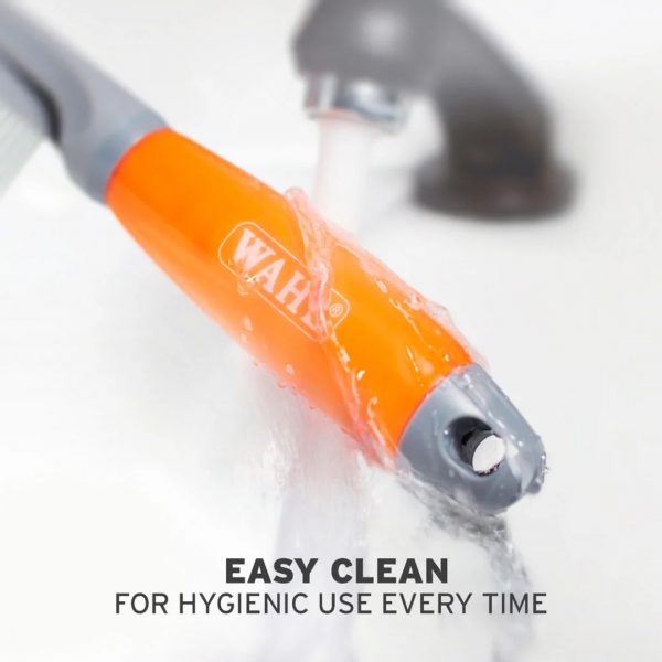 WAHL Grooming Comb Easy Clean 1080px Close-up action shot of the orange and grey WAHL grooming comb handle being rinsed directly under a running water stream from a chrome tap to highlight its waterproof, low-maintenance design. Water droplets splash off the smooth, translucent orange surface. Bold text at the bottom reads "EASY CLEAN FOR HYGIENIC USE EVERY TIME"