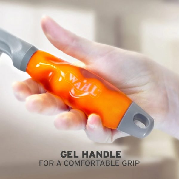 WAHL Grooming Comb Gel Handle 1080px Detailed close-up macro shot of a hand compressing the soft, translucent orange gel handle of a WAHL pet grooming comb, showcasing its ergonomic design and squishy texture. The handle features a grey trim and a prominent white WAHL brand logo. Bold text at the bottom reads "GEL HANDLE FOR A COMFORTABLE GRIP"