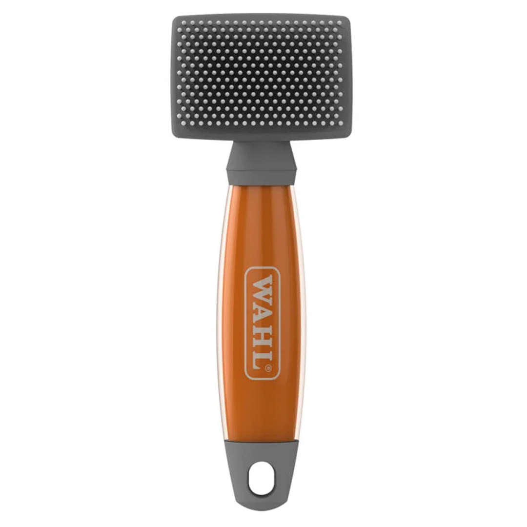 Front studio shot of the WAHL Small Nylon Slicker Brush. The compact grooming tool features a narrow rectangular grey brush head with protective white nylon pins, an orange gel comfort handle with the WAHL logo, and a grey capped base