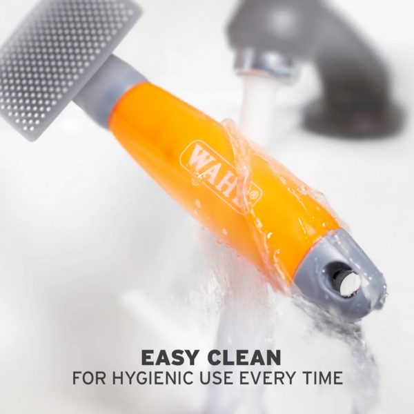 WAHL Nylon Slicker Brush Small Easy Clean 1080px An action shot showing the orange handle of the WAHL slicker brush being rinsed directly under a running bathroom sink tap. Text overlay at the bottom reads: "EASY CLEAN FOR HYGIENIC USE EVERY TIME"